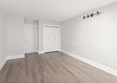 Master bedroom with large closet, hardwood floors, and modern lighting