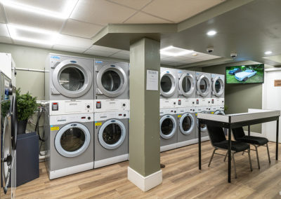 Laundry center with stacked, front-loading washers and dryers with flatscreen television, table and chairs